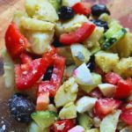 Fresh potato salad with boiled eggs, cucumber, tomato, and olives, a colorful and healthy Mediterranean-inspired dish.