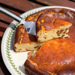 A slice of Basque cheesecake resting on top of the whole cheesecake.