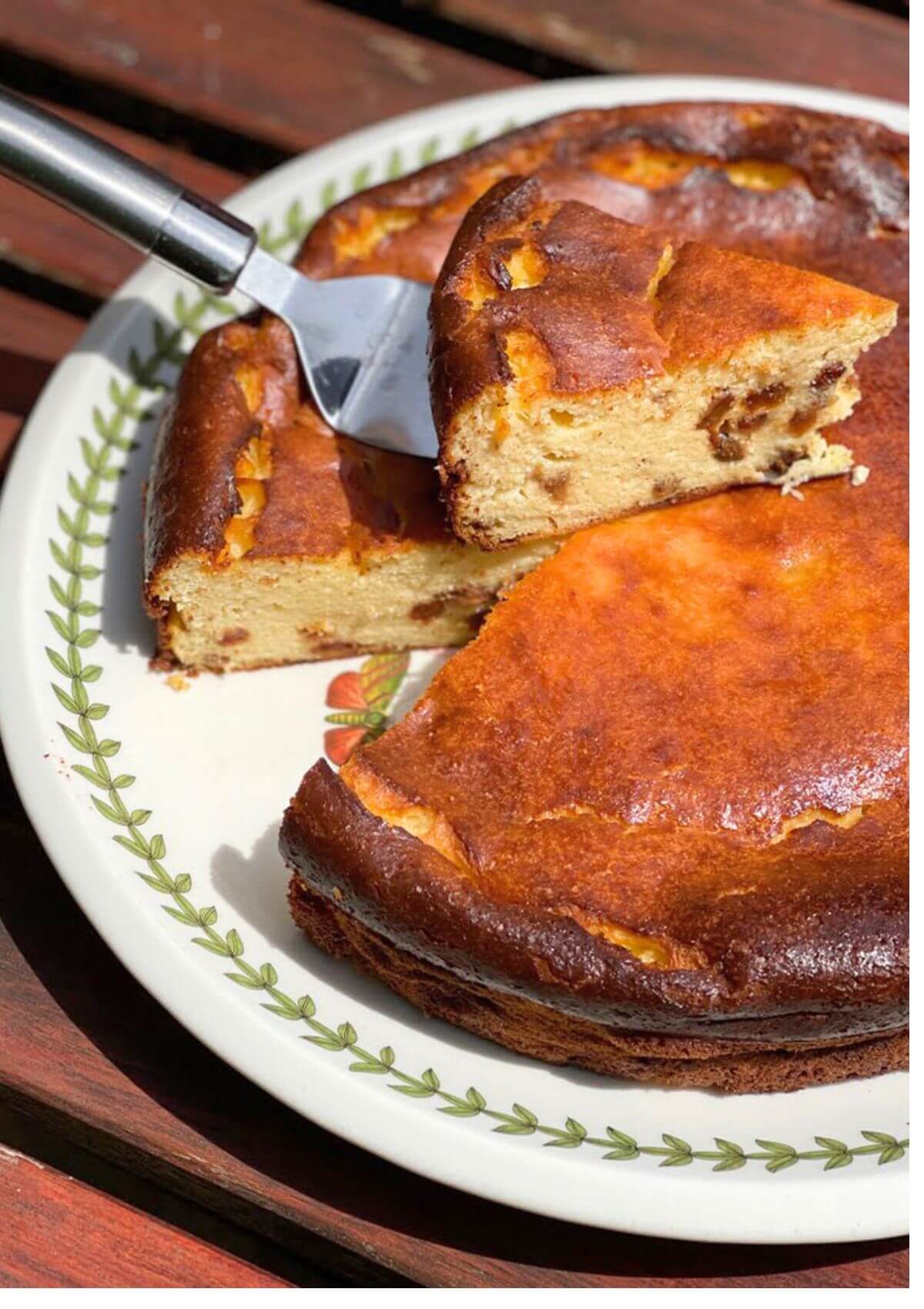 A slice of Basque cheesecake resting on top of the whole cheesecake.