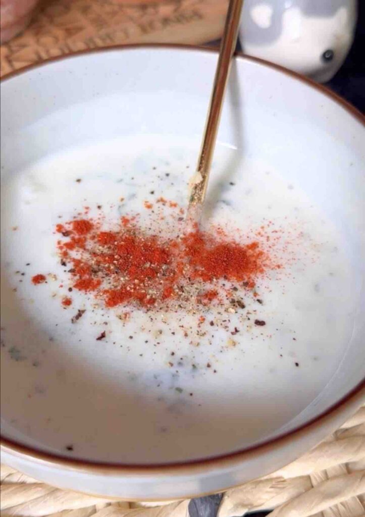 Mix crushed garlic, paprika, chopped parsley, and a pinch of salt and pepper in a small bowl, ready to be mixed.