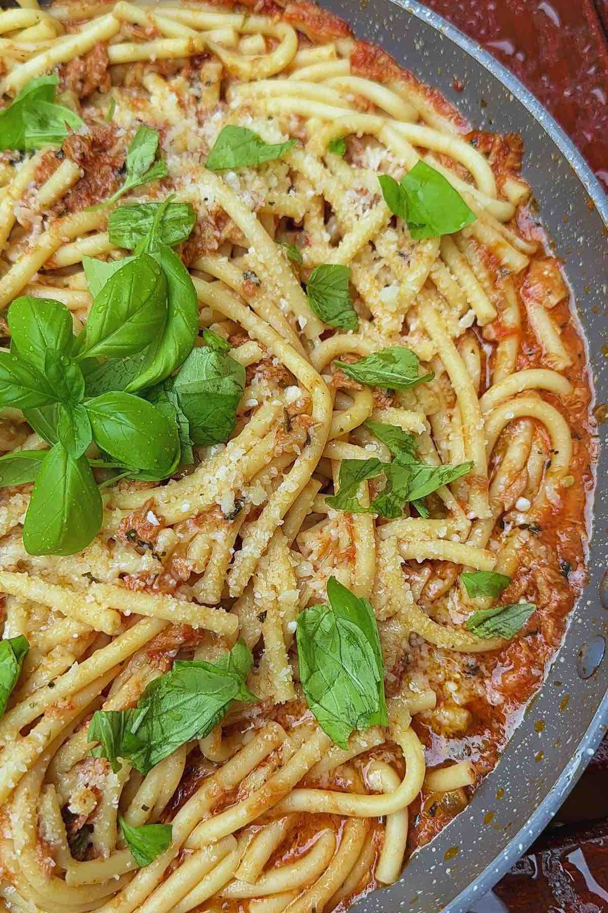 Tuna, caper & chilli bucatini  in a large pan garnished with fresh basil 