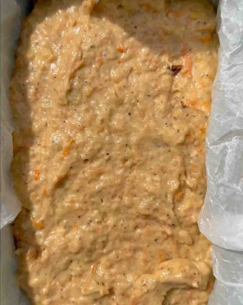 A loaf pan lined with parchment paper, filled with vegan banana bread batter, ready to be placed in the oven for baking