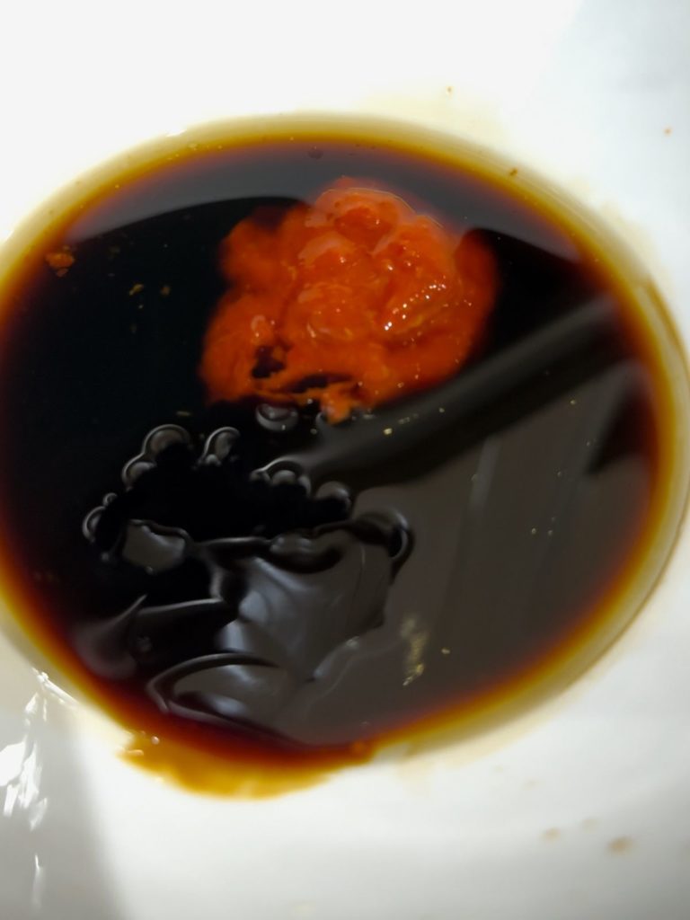 Sesame oil, soy sauce, oyster sauce, and chili sauce or paste in a bowl.