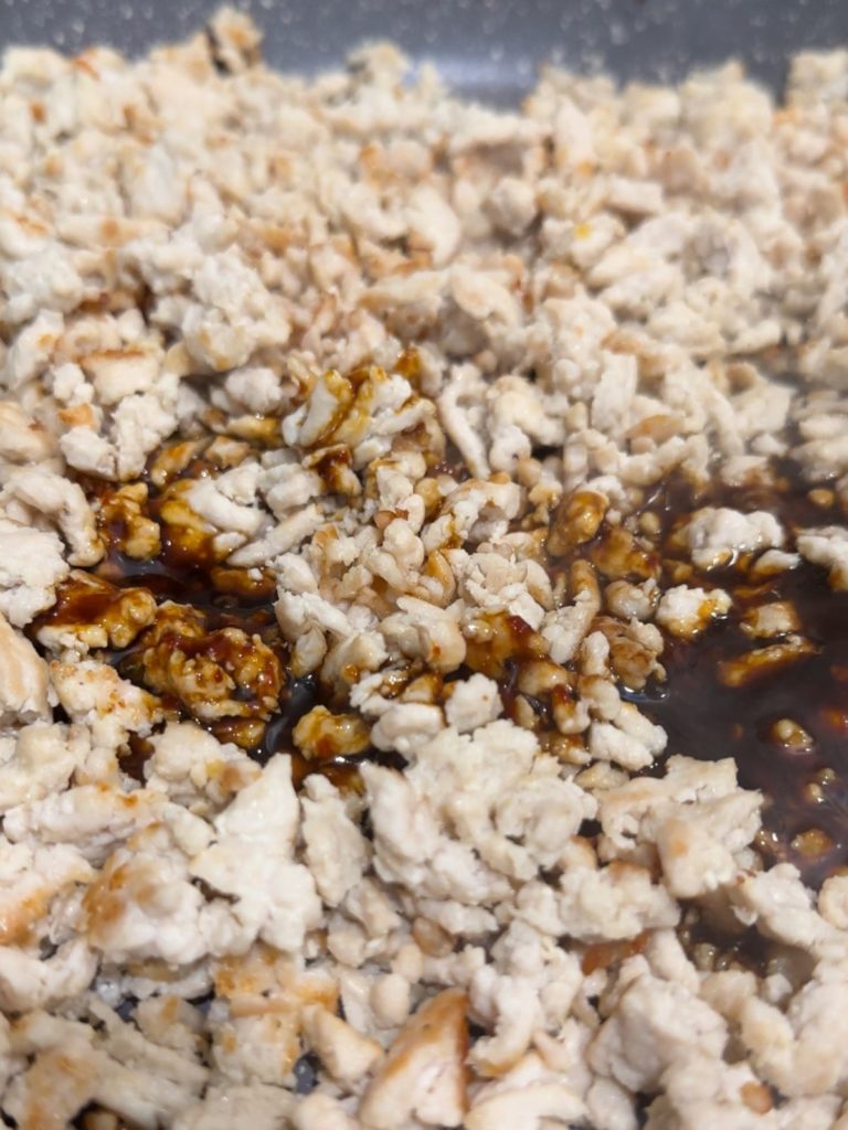 Sesame oil, soy sauce, oyster sauce, and chili sauce or paste in a bowl, added to a pan with cooked turkey mince for making Korean-style keema. 