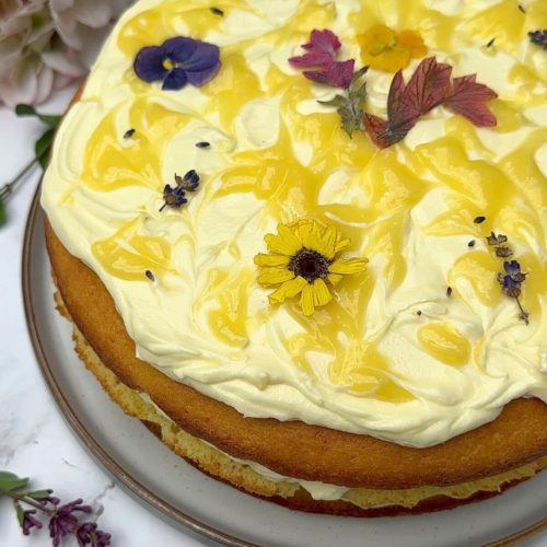 Three Layer Lemon Cake decorated with lemon cream cheese frosting, lemon curd swirls and edible flowers.