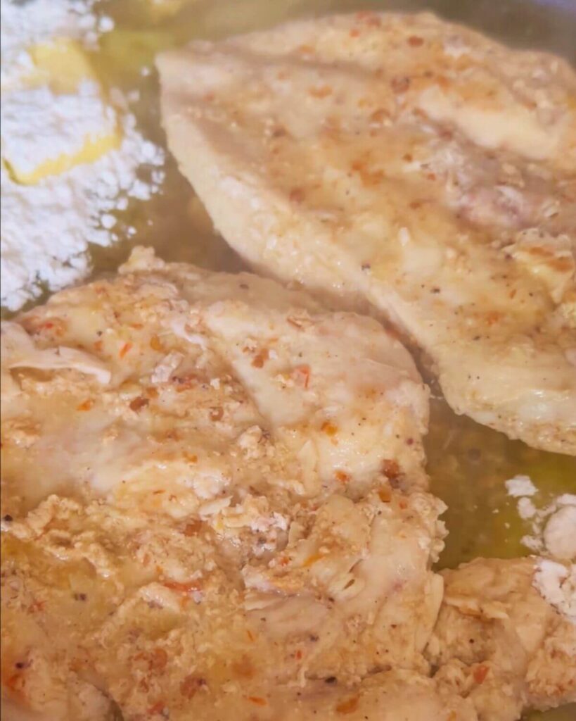 A photo showing two cooked pieces of chicken breast in a pan.