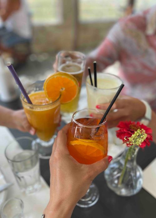 4 glasses with drinks: fresh Orange juice, banana smoothie, beer and Aperol Spritz