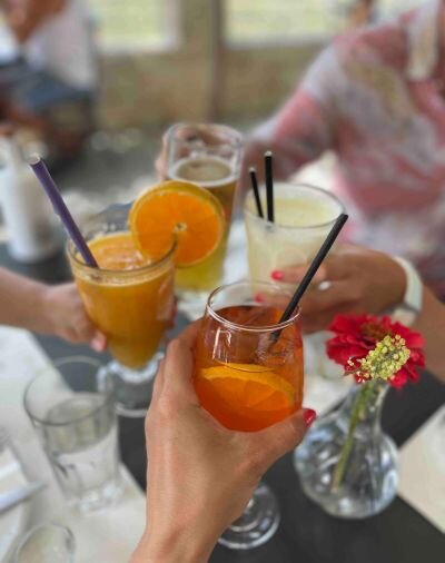 4 glasses with drinks: fresh Orange juice, banana smoothie, beer and Aperol Spritz