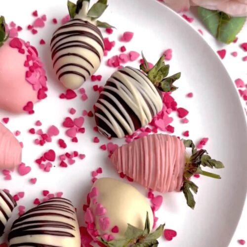 Chocolate-covered strawberries arranged neatly on a white plate, featuring a smooth chocolate coating with some drizzled in white chocolate for decoration