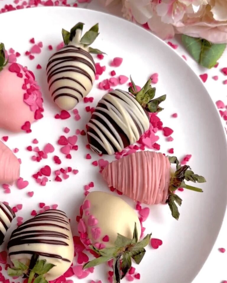 Chocolate-covered strawberries arranged neatly on a white plate, featuring a smooth chocolate coating with some drizzled in white chocolate for decoration