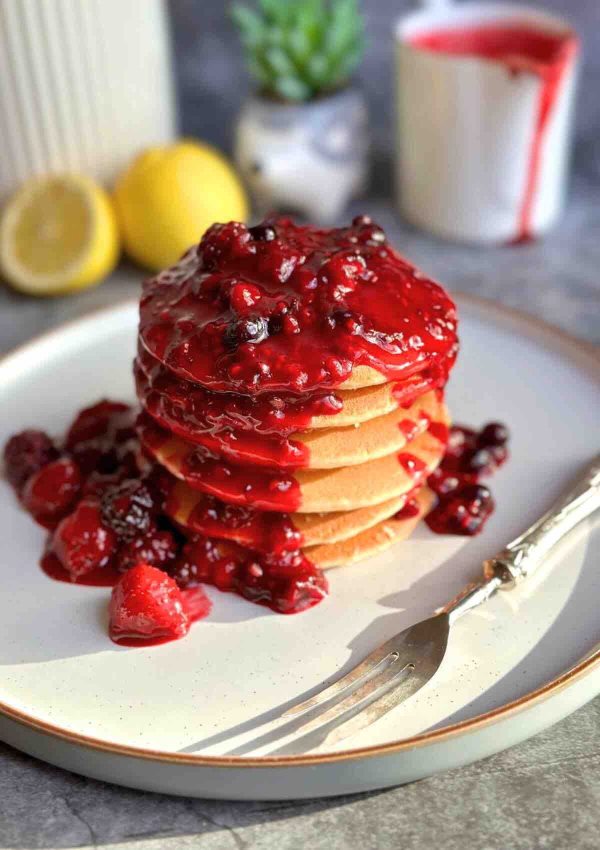 A tower of pancakes topped with berry sauce