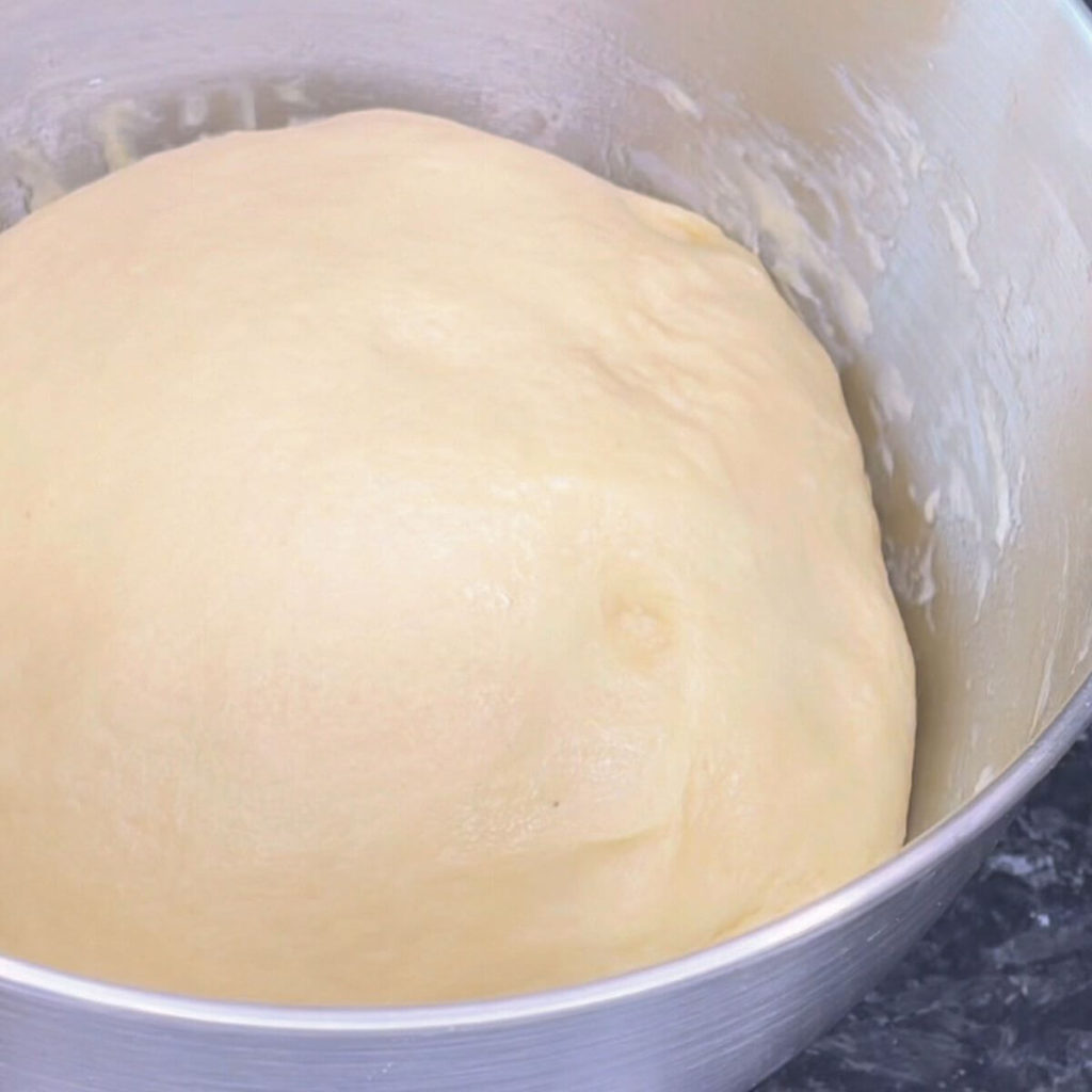 Raw dough in a mixing bowl, ready to rise for one hour