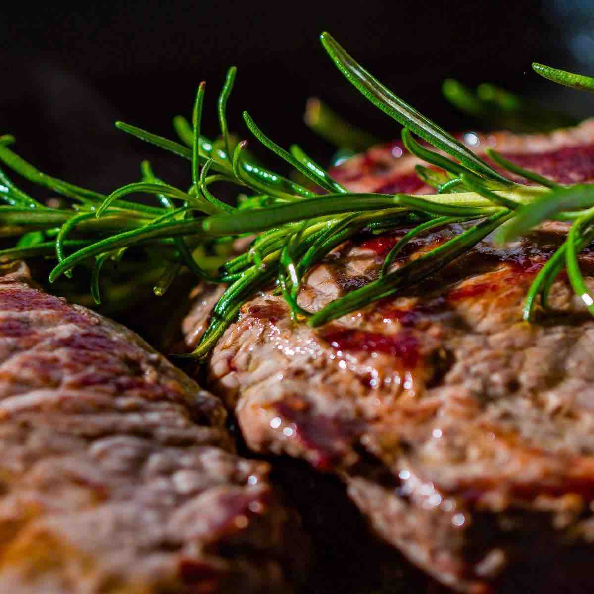 Grilled beef steak garnished with a fresh rosemary spring. 