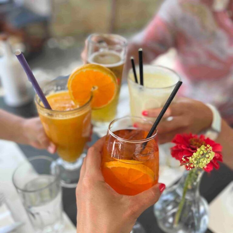 4 glasses with drinks: fresh Orange juice, banana smoothie, beer and Aperol Spritz