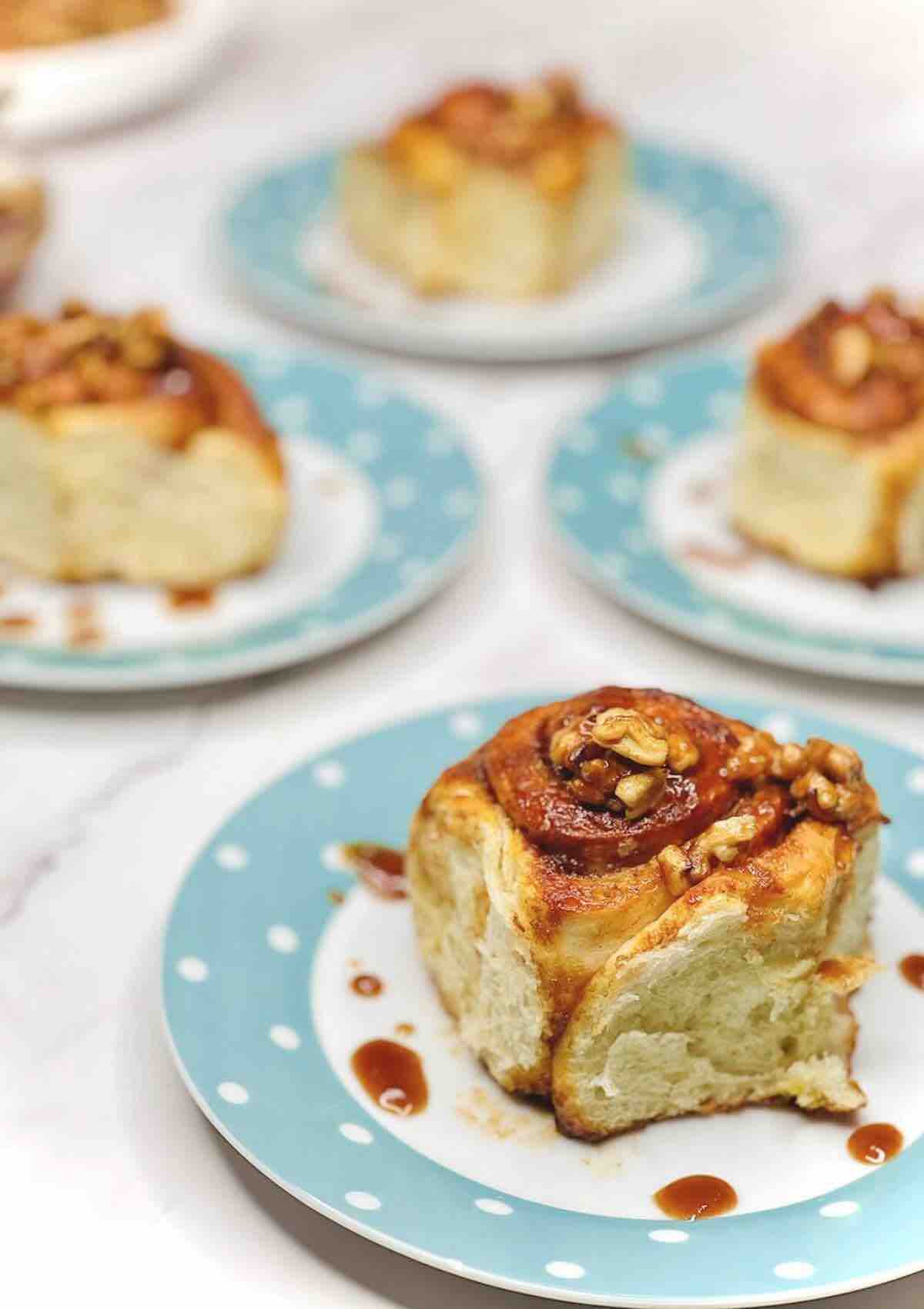 A portion of Biscoff Cinnamon Rolls on a plate with other three in the background