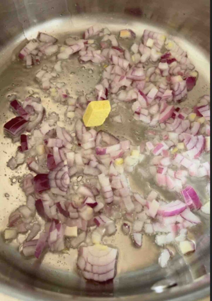 Onions, salt, pepper, and a stock cube being sautéed in a pan.