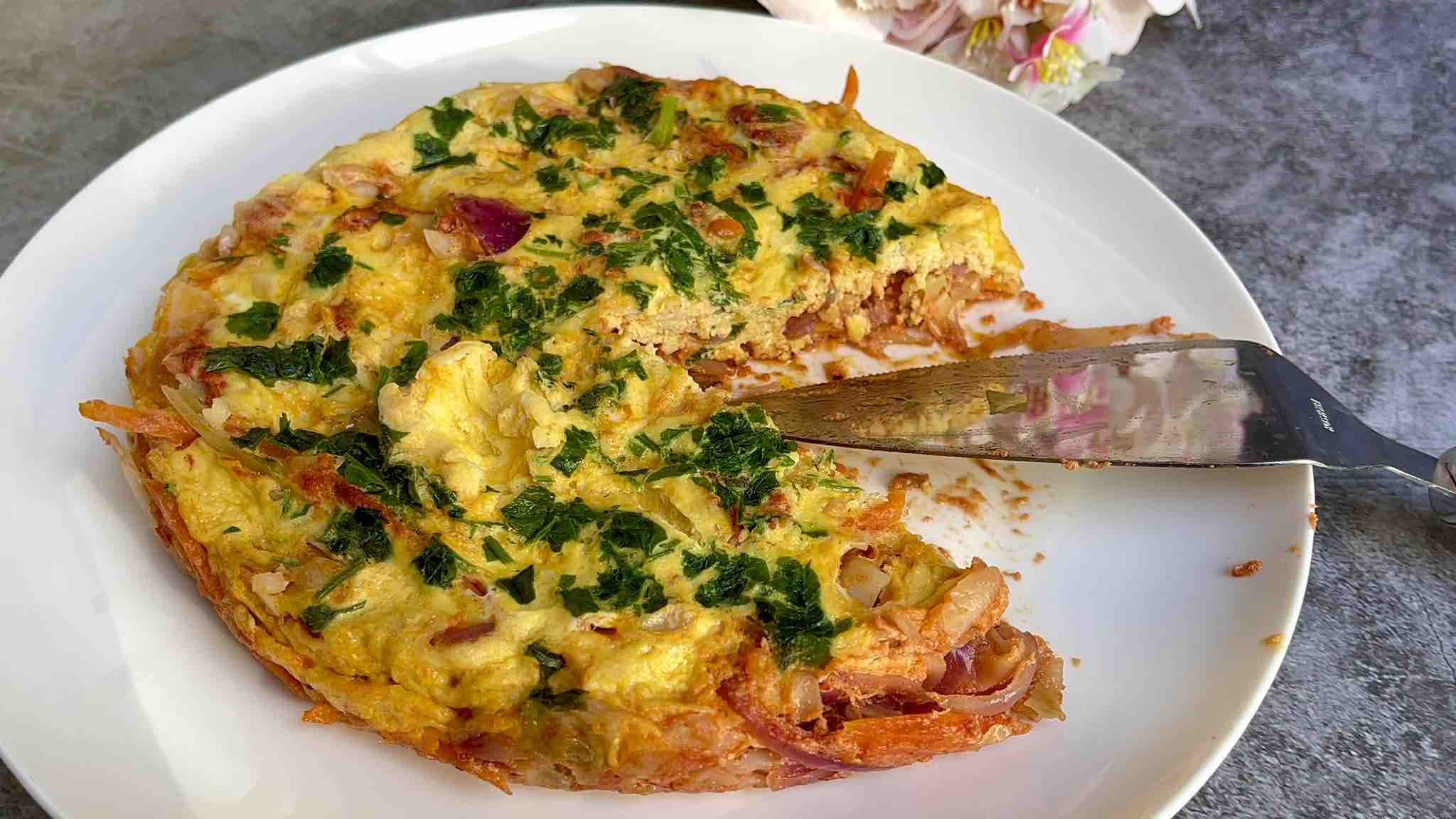 Easy Cabbage Frittata on a plate, with a piece cut out, showcasing the veggie-packed filling and golden-brown crust.