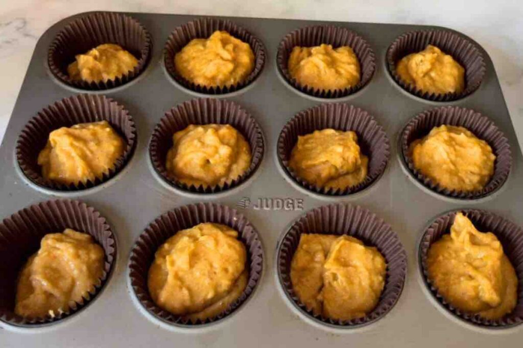 Batter evenly distributed in 12 cupcake liners, ready for baking.