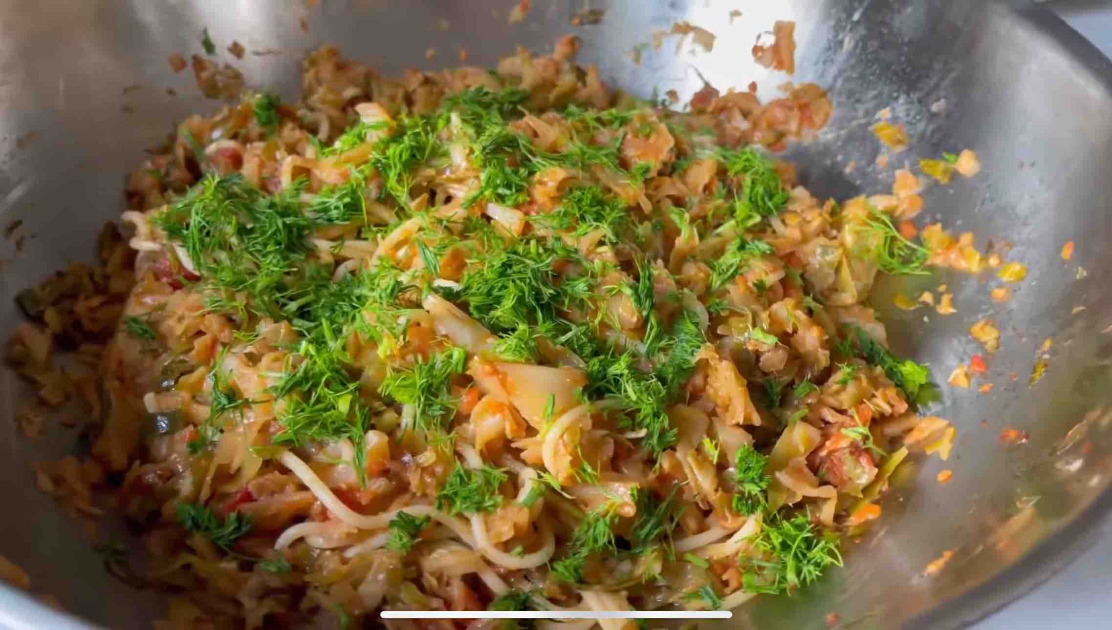 Cabbage pasta garnished with chopped dill in a wok, ready to be served.