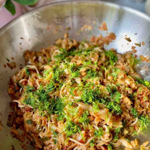 Cabbage pasta garnished with chopped dill in a wok.