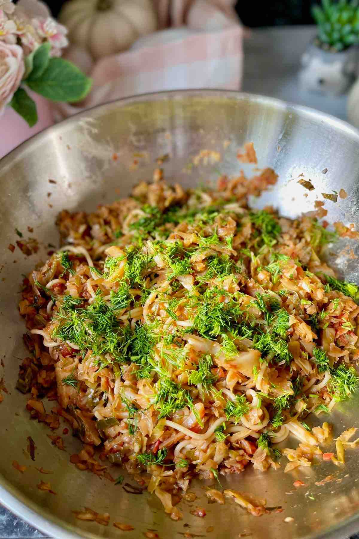 Cabbage pasta garnished with chopped dill in a wok.