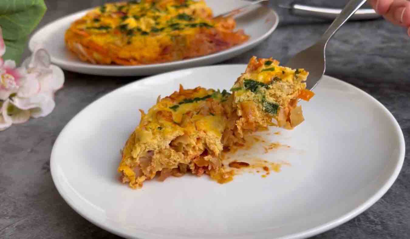 A slice of cabbage frittata on a plate, showcasing its golden crust and vibrant green cabbage pieces.