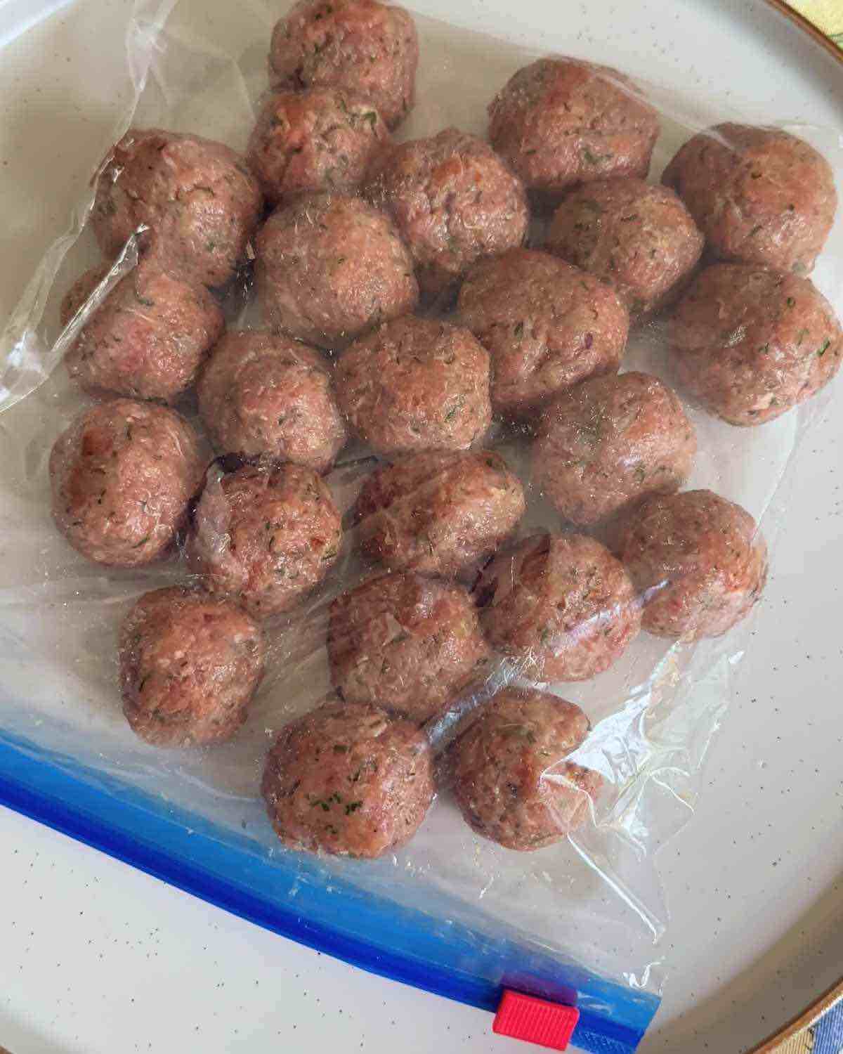 Shaped meatballs placed inside a zip-top bag, ready to be sealed and stored in the freezer for future use.