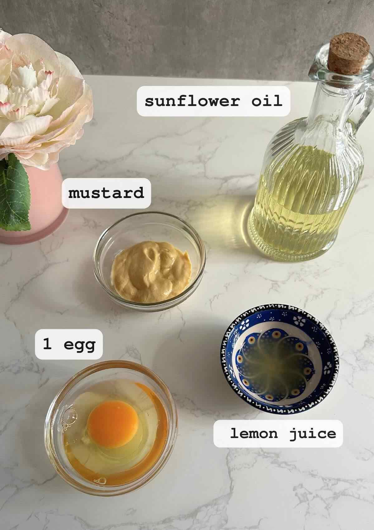 Photo showing the ingredients for making mayonnaise with only 4 ingredients, each labeled clearly: sunflower oil, egg, mustard, and lemon juice.