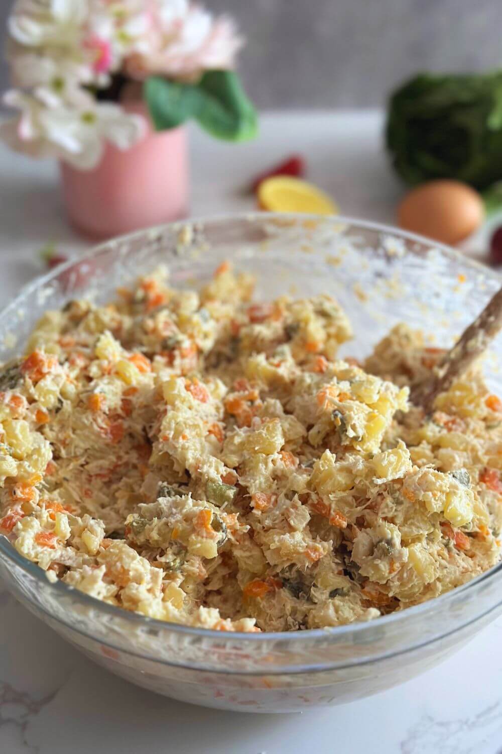 A bowl of freshly mixed Olivier Salad (Salata de Boeuf), a traditional Romanian dish made with tender beef or chicken, mixed vegetables, potatoes, pickled cucumbers, and a creamy mayo dressing. The salad is ready to be transferred to a serving plate and decorated for special occasions and holiday celebrations.