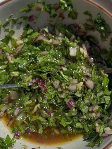 Chimichurri sauce with red onion, parsley, coriander, garlic, vinegar, olive oil, chili, salt, and pepper.