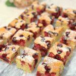 Squares of Morello Cherry Sponge Cake displayed on a marble surface, showcasing the moist center filled with juicy cherries.