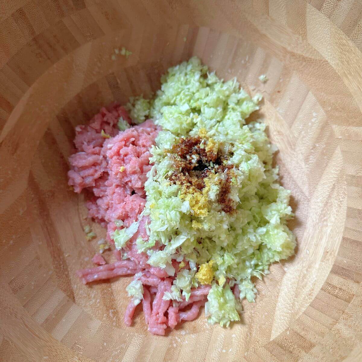  Ingredients for turkey wontons: ground turkey, scallion, garlic, lemon zest, ginger, soy sauce, cabbage, and oil, ready to be mixed in a bowl.