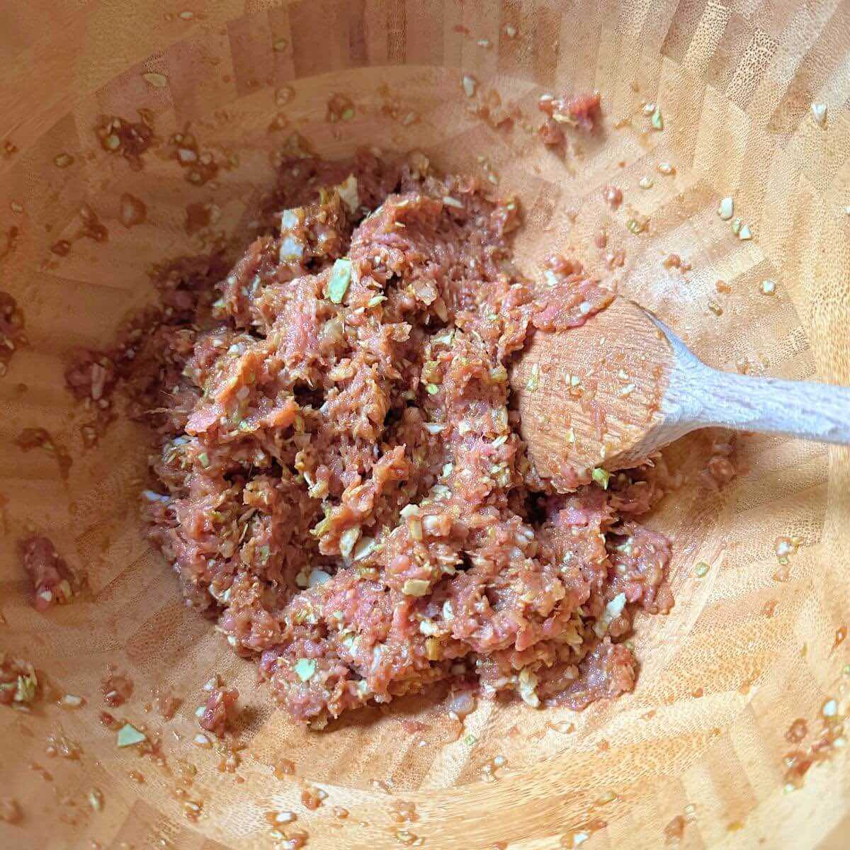 Ingredients for turkey wontons: ground turkey, scallion, garlic, lemon zest, ginger, soy sauce, cabbage, and oil, mixed in a bowl.