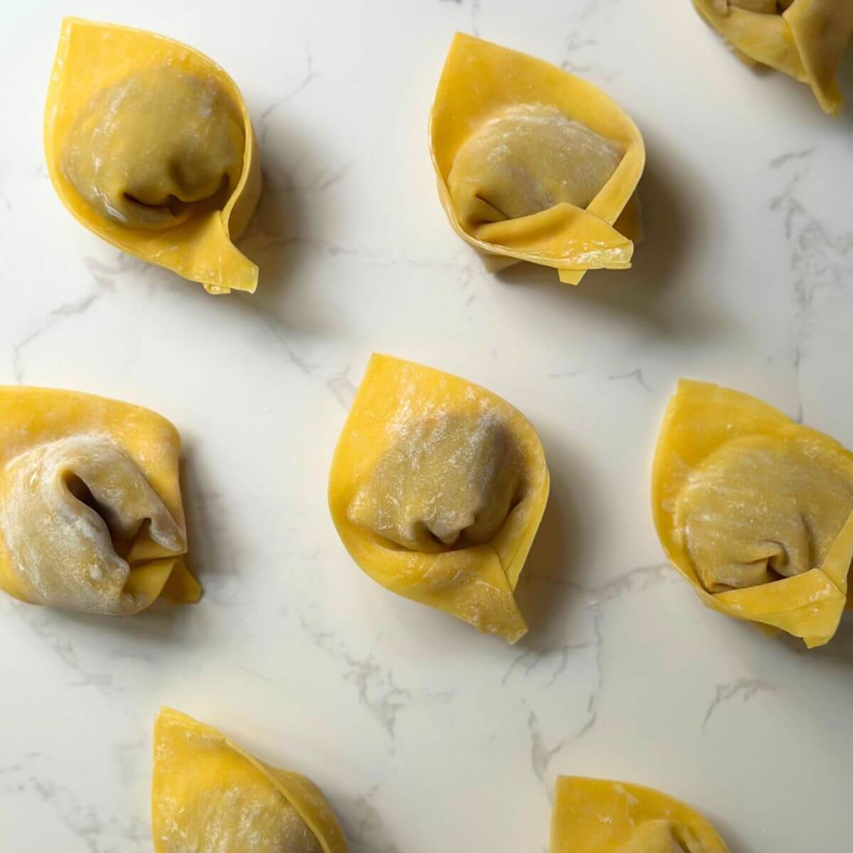 Perfectly folded turkey wontons arranged and ready to be cooked.