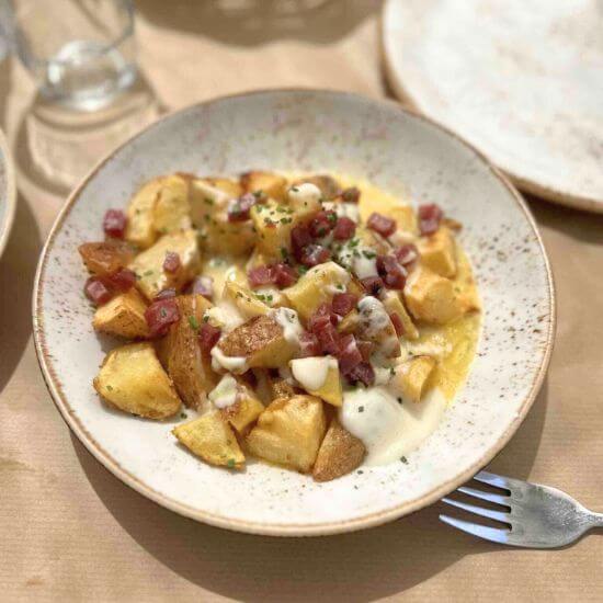 Fried potatoes cubes with melted cheese and crunchy diced pancetta.