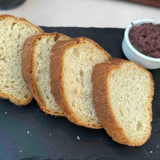 Toasted bread slices served with a small bowl of olive dip, perfect for dipping or spreading.