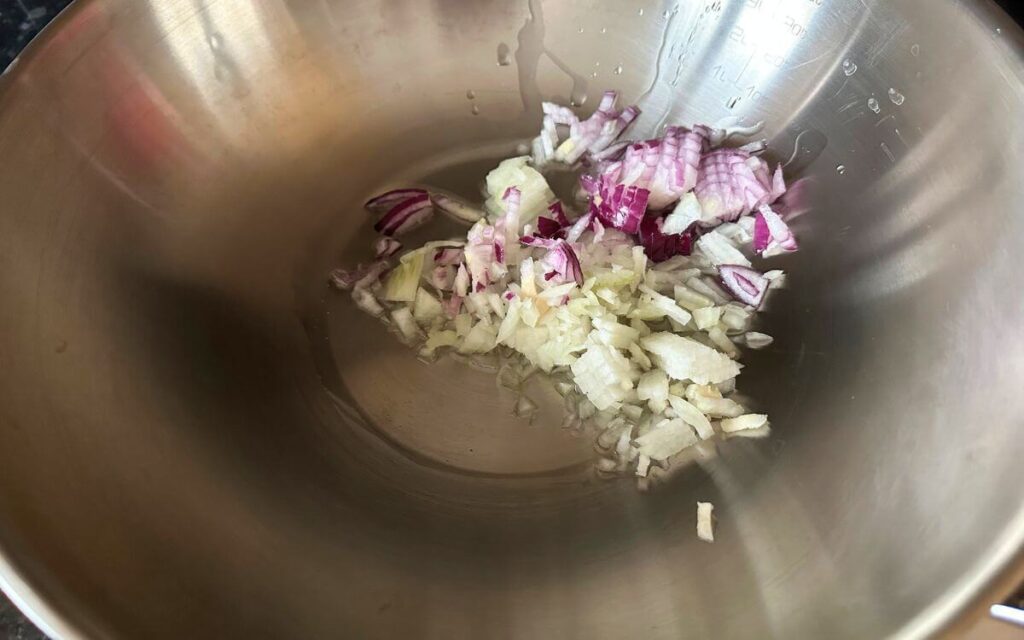 Chopped onions and olive oil in a pan, ready to be sautéed.