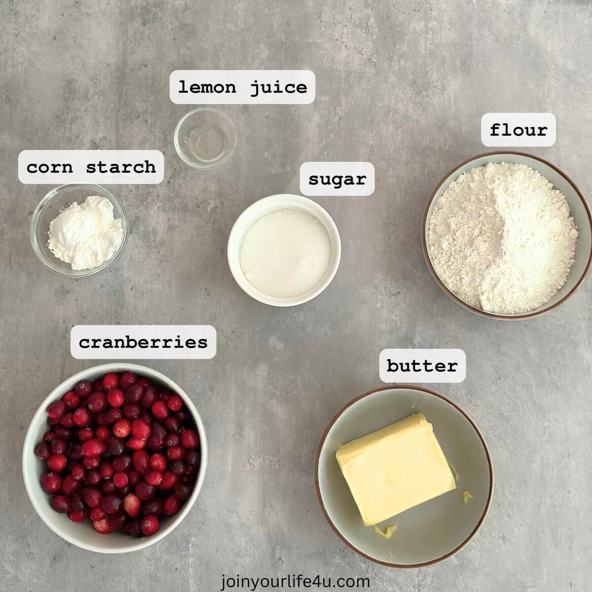 Ingredients displayed individually on a table: butter, sugar, flour, cranberries, cornstarch, and lemon juice.