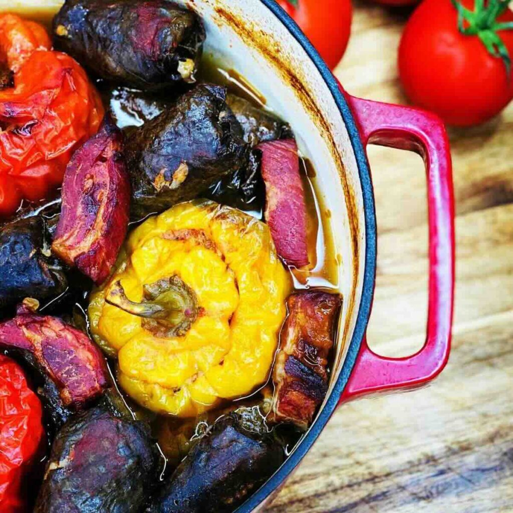 Stuffed grape leaves and bell peppers in a re ceramic pot